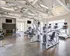 Modern fitness center featuring state-of-the-art gym equipment, including treadmills and weight machines, with bright natural lighting and sleek architectural design.