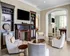 Luxurious living room featuring elegant chairs, a classic fireplace, built-in bookshelves, and seamless flow into an entertainment area with a pool table.