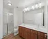 Elegant bathroom with double sinks, modern lighting, and glass-door shower featuring stylish wood cabinetry.