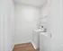Modern laundry room with sleek washer and dryer, featuring elegant wooden flooring and ample shelving space.