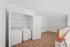 Bright laundry area with modern washer and dryer, featuring elegant wooden flooring and ample shelving space.