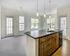 Bright and modern kitchen with sleek island, stylish pendant lighting, and abundant natural light from large windows.
