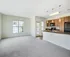 Bright and spacious open-plan apartment with large window, elegant kitchen with modern appliances, and cozy plush carpet.