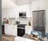 Bright, modern kitchen with sleek stainless steel appliances, abundant white cabinetry, and stylish wood flooring. Perfect for culinary creativity.