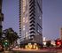 Stunning high-rise apartment building with modern glass architecture, illuminated warmth from within, offering urban living in a vibrant cityscape setting.