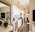 Modern kitchen with sleek white cabinetry, stainless steel appliances, and elegant wood flooring, opening to a cozy dining area.
