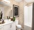 Elegant bathroom with chic leaf-patterned wallpaper, modern white vanity, and stylish framed artwork.