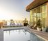 Luxurious rooftop pool with breathtaking city and waterfront views, stylish loungers, and elegant glass-paneled architecture.