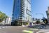 Modern high-rise building with sleek architecture and expansive glass windows located on a bustling city corner, ideal for urban living.