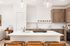 Kitchen with wood cabinets, white countertops and island seating at Sonora in Austin, TX