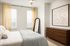 Bedroom with plush bed, wood dresser and full-length mirror at Sonora in Austin, TX
