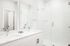 White bathroom with double-sink vanity and glass shower at Sonora in Austin, TX
