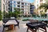 Luxurious apartment courtyard with a poolside lounge, stylish outdoor dining area, and a foosball table, surrounded by lush greenery for a perfect leisure escape.