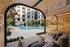 Luxurious apartment courtyard with contemporary cabana seating, overlooking a pristine swimming pool surrounded by lush greenery.