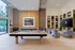 Elegant lounge featuring a billiard table, modern seating, and stylish shelves with decorative elements and plants, creating a luxurious entertainment space.