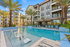Luxurious apartment complex with a sparkling pool surrounded by palm trees and stylish sun loungers, perfect for relaxation and leisure.