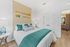 Inviting bedroom with vibrant teal accents, decorative oars on the wall, and elegant bedside lamps for a cozy ambiance.