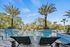 Poolside oasis featuring sleek sun loungers, vibrant palm trees, and a sparkling blue pool under a clear sky.
