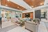 Elegant modern living room with stylish furniture, wood-paneled ceiling, and accent wall, featuring large TV and sliding barn door, creating a chic and cozy atmosphere.