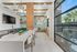 Chic and modern kitchen area featuring a marble island, stylish lighting, and cozy seating with large windows overlooking lush greenery.