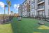 Modern apartment complex with vibrant green lawn, elegant landscaping, and whimsical outdoor seating, perfect for relaxation and leisure.