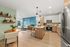 Modern open-concept living space featuring a stylish kitchen with island, spacious living room with vibrant blue accent wall, and cozy dining area. Perfect blend of functionality and contemporary design.
