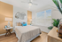 Charming bedroom with elegant decor, featuring a cozy bed, modern lamps, unique wall mirrors, and abundant natural light through wide windows.