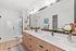 Elegant bathroom with double vanity, sleek white countertop, and stylish fixtures, featuring a spacious glass-enclosed shower and modern decor.