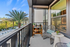 Charming balcony view with cozy wicker seating, vibrant potted plants, and refreshing palm trees under a bright blue sky.