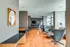 Modern, sunlit lounge area with stylish furniture, wood flooring, and a wall-mounted TV, ideal for relaxation and gatherings.