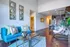 Modern living room with vibrant decor featuring a blue sofa, accent pillows, and a unique hanging chair, complemented by stylish mirrors and warm wooden flooring.