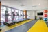 Modern apartment gym with bright yellow flooring, featuring multiple treadmills and colorful exercise balls, inviting a vibrant and active lifestyle.