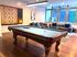 Inviting game room featuring a sleek pool table, modern seating area, and a wall-mounted Scrabble board, perfect for entertainment and relaxation.