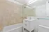 Modern bathroom with elegant beige tiles, sleek white vanity, and spacious tub, offering a serene oasis for relaxation.