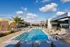 Exquisite rooftop pool area with modern lounge chairs and tropical palm trees under a vibrant blue sky.