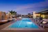 Luxurious rooftop pool with stylish loungers and chic wooden cabanas, set against a stunning sunset backdrop.