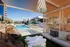 Luxurious poolside retreat featuring stylish outdoor seating, elegant cabanas, and a refreshing swimming pool under clear blue skies.