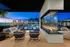 Luxurious outdoor seating area with modern fireplace overlooking a serene pool and stylish cabanas against a stunning sunset backdrop.