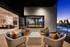 Luxurious outdoor patio with elegant wicker seating and a modern fireplace overlooking a stunning sunset and pool view.