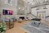 Luxurious loft-style living room with high ceilings, modern decor, and a billiards table, perfect for entertaining.