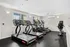 Modern fitness room with state-of-the-art treadmills, exercise bikes, and ample natural light from large windows.