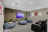 Chic home theater room featuring cozy bean bags, leather recliners, and a large wall-mounted TV with stylish artwork and soft lighting.