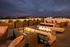 Luxurious rooftop lounge with cozy seating and a sleek fire pit, offering a stunning city view at dusk.