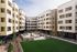 Modern apartment complex with spacious courtyards, lush green lawns, and stylish outdoor seating, offering a vibrant community living experience.