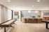 Modern open-concept living space featuring a chic kitchen island with bar stools, elegant pendant lighting, and stylish shuffleboard table.