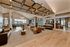 Luxurious open-concept living area featuring modern decor, plush leather sofas, and a chic chandelier in a sunlit spacious room.