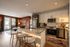 Contemporary kitchen with sleek cabinetry, spacious granite island, and cozy dining stools, elegantly lit by natural sunlight.