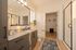 Elegant bathroom with modern fixtures, a sleek granite countertop, spacious walk-in closet, and a stylish glass-enclosed shower.