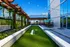 Modern rooftop patio featuring lush greenery, a bocce court, and stylish outdoor seating with colorful umbrellas.