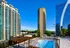 Luxurious high-rise apartments with a stunning cityscape view, featuring a modern swimming pool and vibrant surroundings.